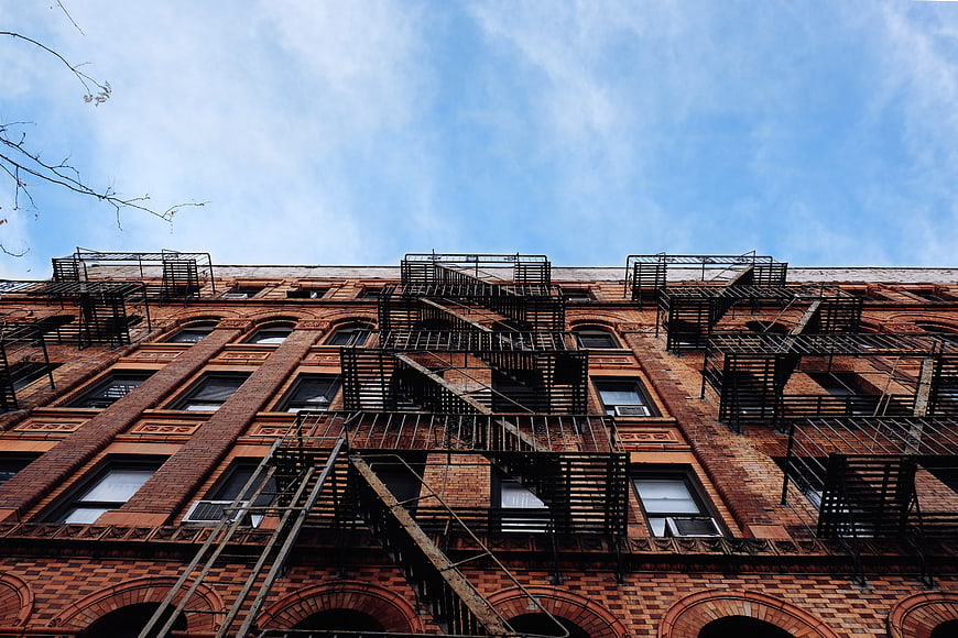 Low angle view of red brick building with black fire escapes