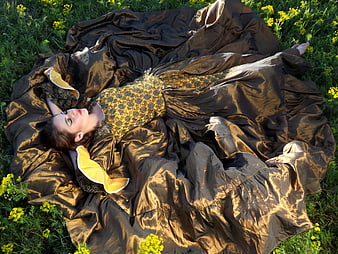 Woman in Golden Dress Lying in Field of Yellow Flowers
