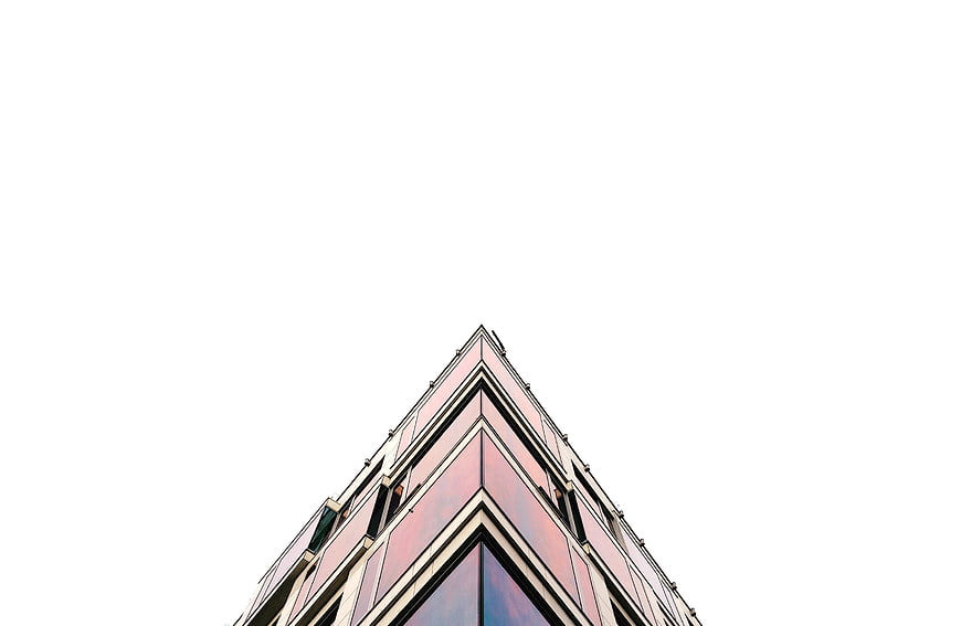 Low angle view of modern glass skyscraper against white sky