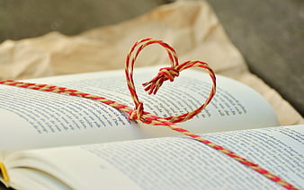 Red and yellow string heart on open book pages