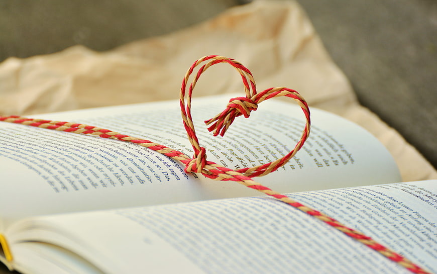 Red and yellow string heart on open book pages