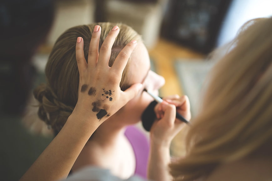 Makeup artist applying eyeshadow with swatches on hand