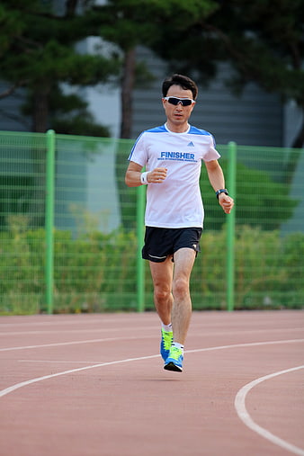 Male runner wearing sunglasses on an outdoor athletics track
