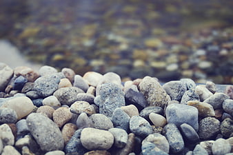 Close-up of smooth river stones and pebbles with blurred water background