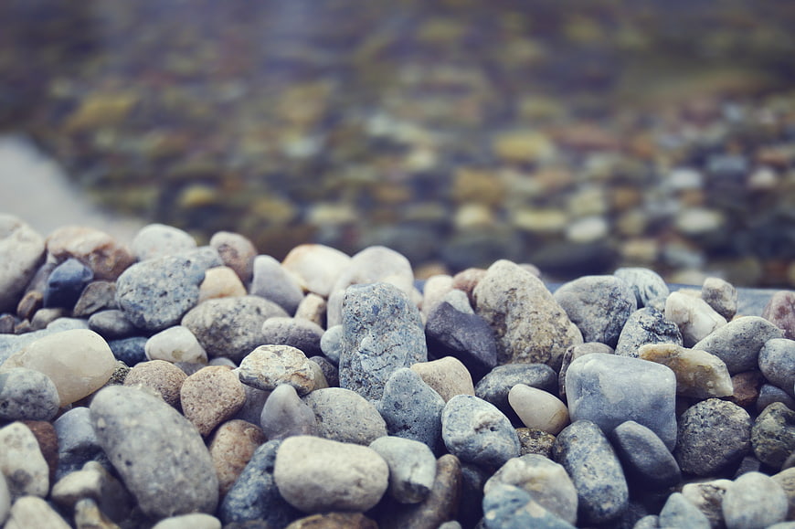 Close-up of smooth river stones and pebbles with blurred water background