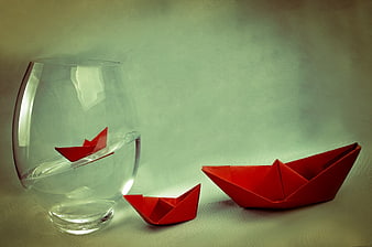 Red origami paper boats floating in a glass of water