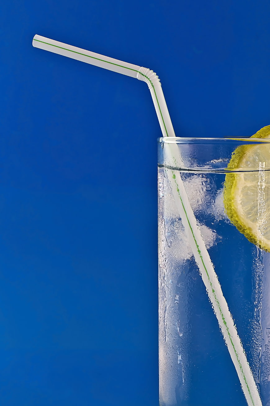 Refreshing Cold Drink with Lemon Slice and Straw on Blue Background