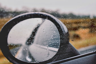 Close-up of car side mirror with raindrops on a rainy day