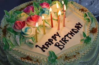 Heart-shaped birthday cake with lit candles and frosting roses