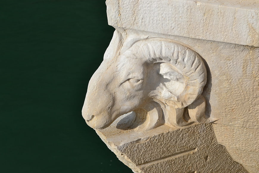 Close-up of ancient stone ram head sculpture on bridge