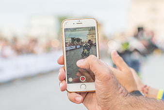 Hand holding smartphone recording motorcycle stunt