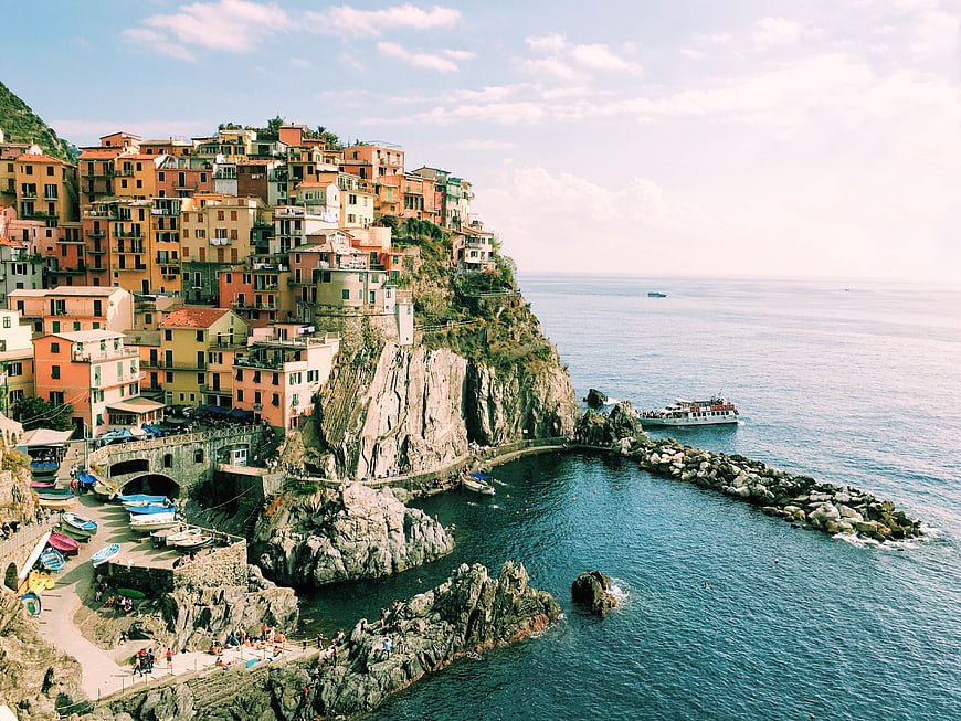 Colorful cliffside village in Cinque Terre, Italy with boats and sea