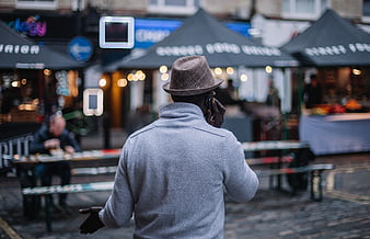 Man in Fedora Talking on Phone at Outdoor Market
