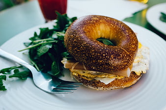 Delicious Bagel Sandwich with Eggs and Ham on White Plate