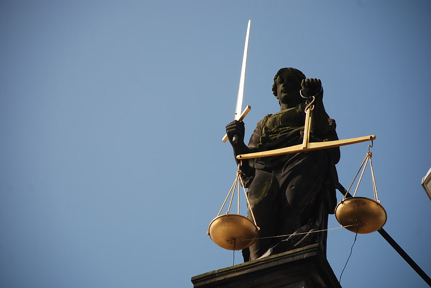 Lady Justice Statue with Sword and Scales Against Blue Sky