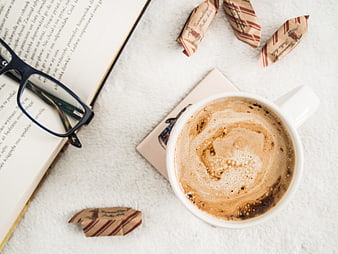 Flat lay of coffee, book, glasses, and candies on white background