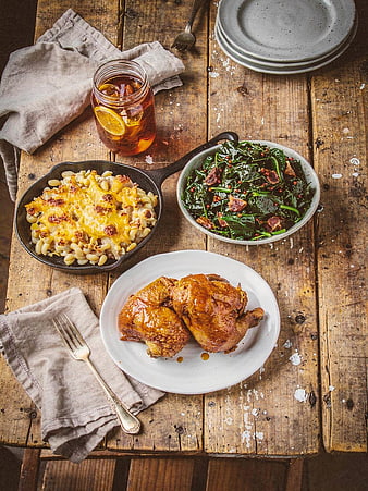 Overhead view of roasted chicken, mac and cheese, and greens on rustic wood