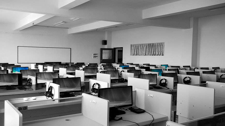 Empty modern computer lab with rows of desktops and headphones