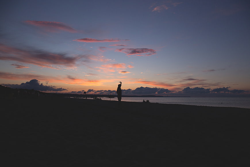 Silhouette of person on beach at sunset with colorful sky