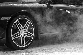 Black and white close-up of a luxury car wheel with steam