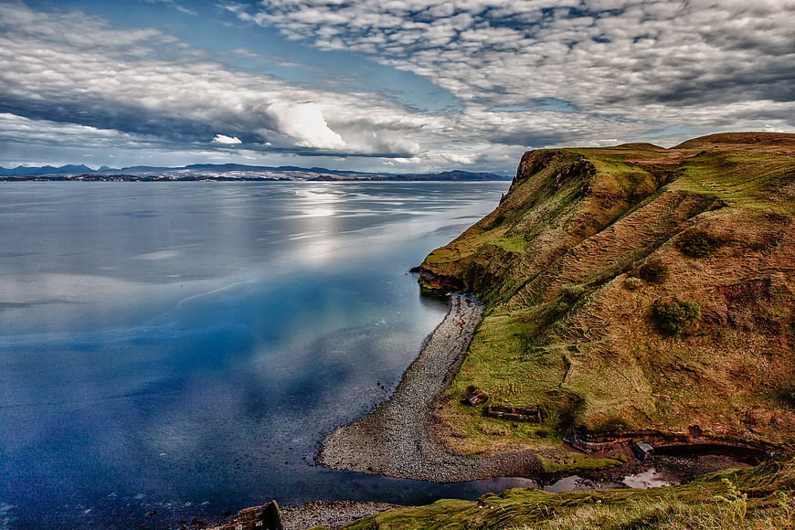 Dramatic coastal landscape with long exposure water and grassy cliffs