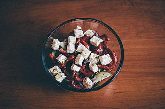 Overhead shot of fresh vegetable salad with feta cheese in glass bowl