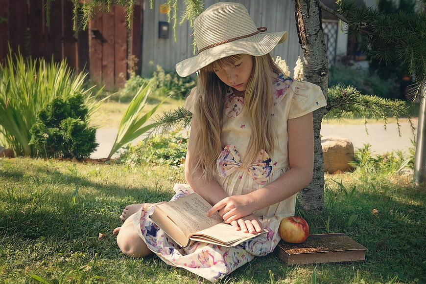 Young girl reading a book in a sunny garden