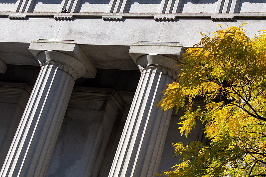 Classical stone columns with vibrant yellow autumn leaves