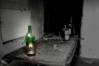 Abandoned green wine bottle on dusty table in dark room