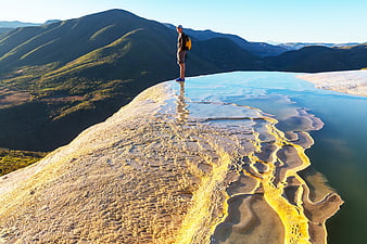 Hiker standing on granite rock with water reflection and mountain view