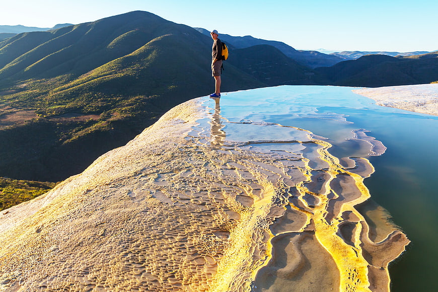 Hiker standing on granite rock with water reflection and mountain view