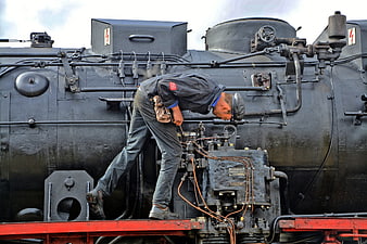 Railroad worker inspecting vintage steam locomotive engine