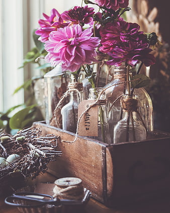 Rustic dahlia flowers in glass bottles with twine and tag
