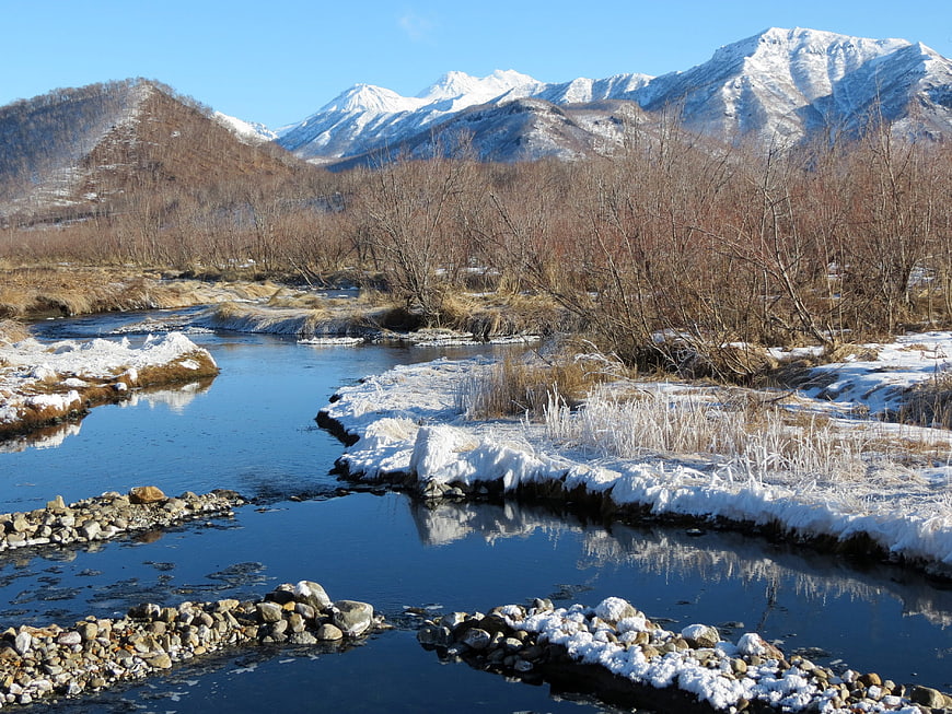 Snowy River Winding Through Winter Valley with Mountains