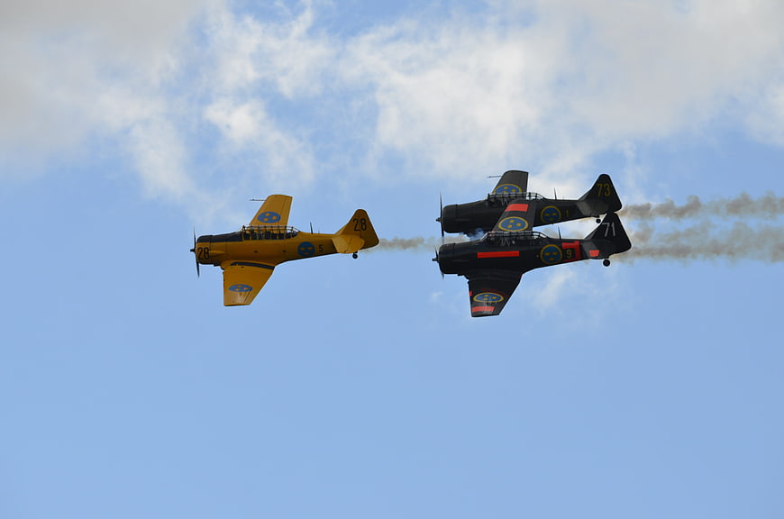 Vintage propeller planes flying in formation with smoke trails