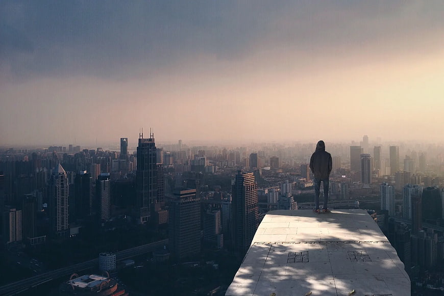 Lone Figure Standing on Rooftop Overlooking Hazy Cityscape