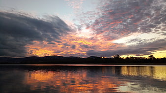 Dramatic sunset over lake with colorful clouds and reflection