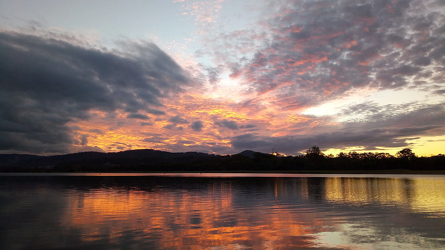 Dramatic sunset over lake with colorful clouds and reflection