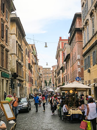 Busy cobblestone street in Rome with outdoor cafes and pedestrians