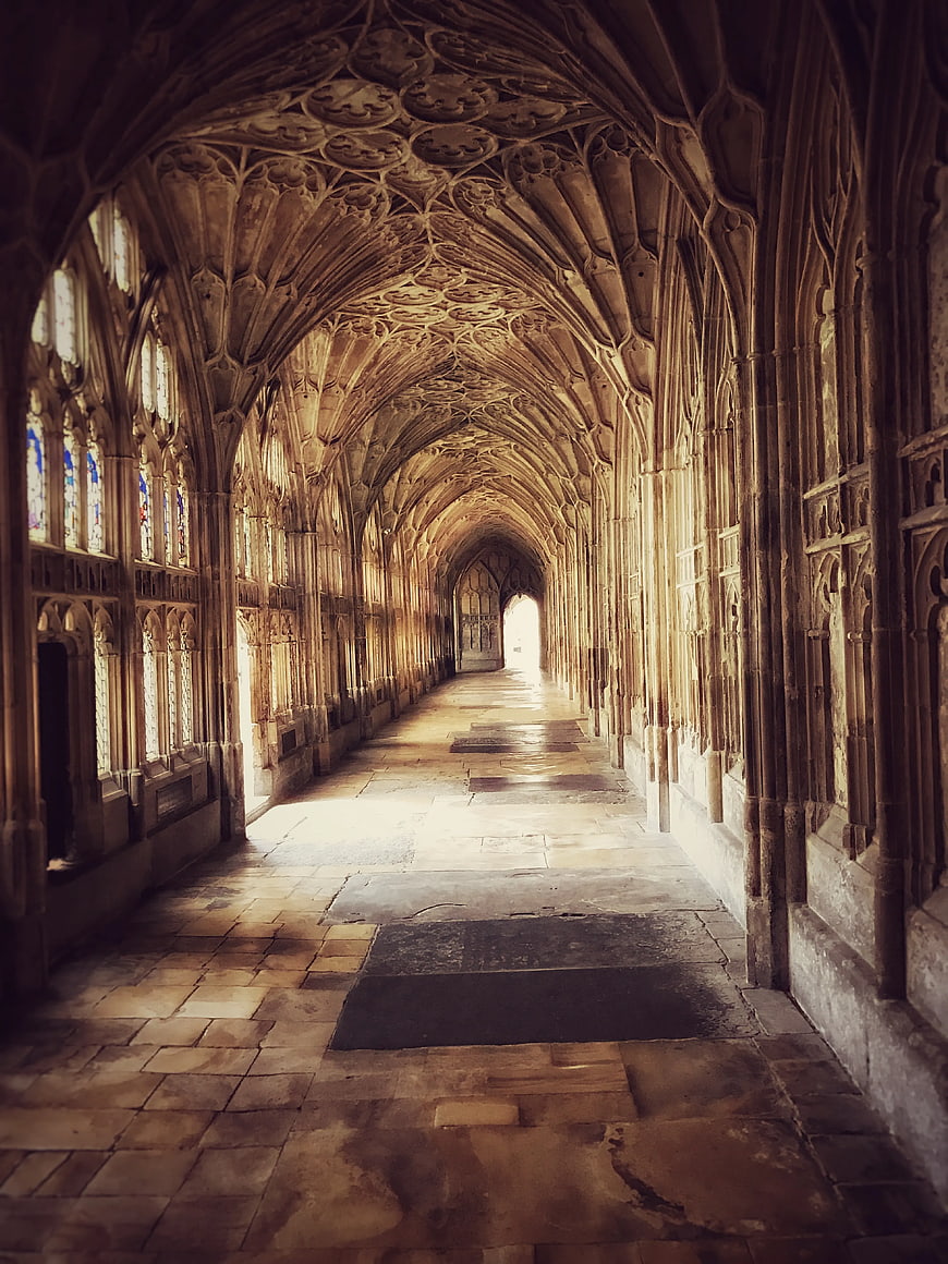 Gothic Vaulted Hallway with Stone Arches and Stained Glass