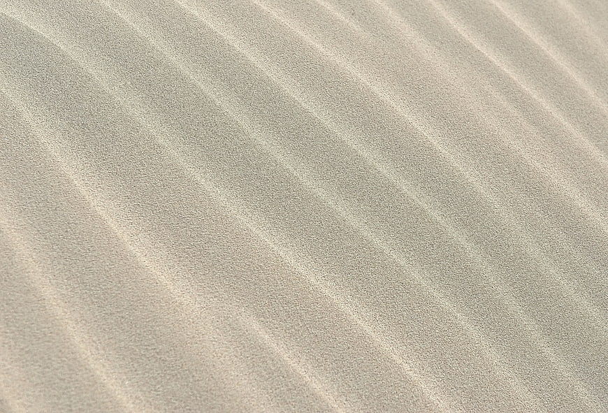 Close-up texture of rippled sand dunes with natural patterns