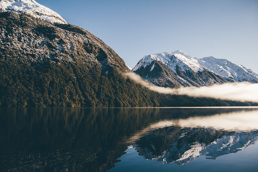 Serene Lake Reflection of Snow-Capped Mountains and Mist