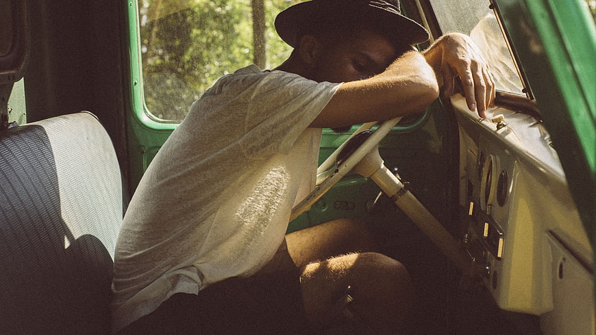 Tired man sleeping in vintage car interior