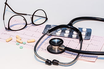 Stethoscope, pills, and ECG print on white background