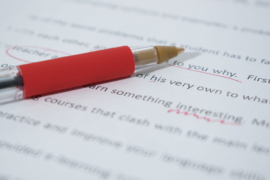 Red pen correcting text on a printed document