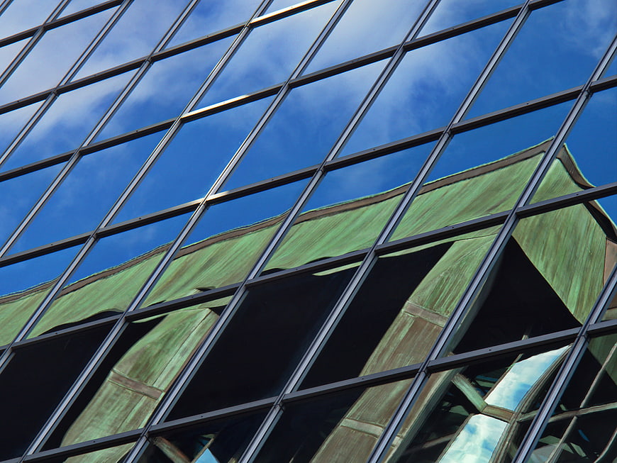 Modern Glass Building Facade with Green Roof Reflection