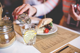 Pouring water with lemon into glass at cafe