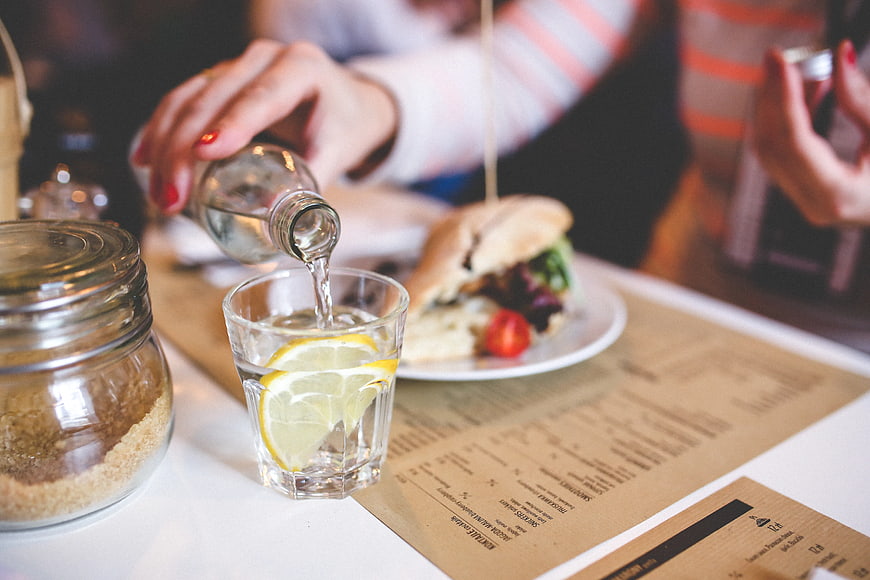 Pouring water with lemon into glass at cafe