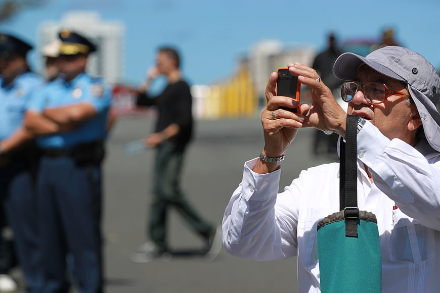 Man Taking Photo with Smartphone Near Police Officers