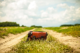 Brown Leather Messenger Bag on Grassy Dirt Road